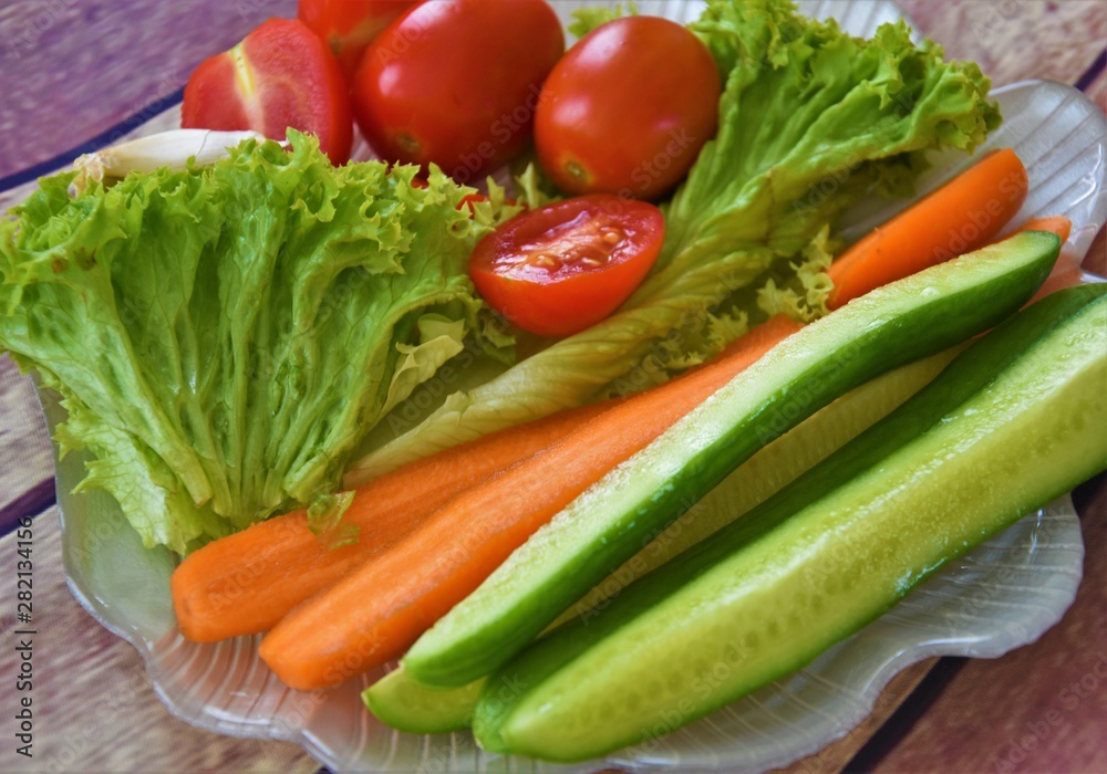 fresh lettuce, tomatoes, cucumbers, carrots and a clove of garlic on a plate of shell fresh lettuce, tomatoes, cucumbers, carrots and a clove of garlic on a plate of shell