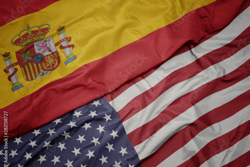 waving colorful flag of united states of america and national flag of spain. macro