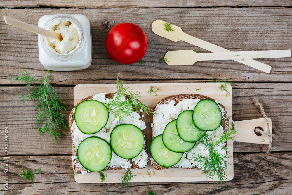 Grilled black bread, soft cheese, cucumber on an old wooden table. Healthy eating, slimming, diet lifestyle conc. Grilled black bread, soft cheese, cucumber on an old wooden table. Healthy eating, slimming, diet lifestyle conc.