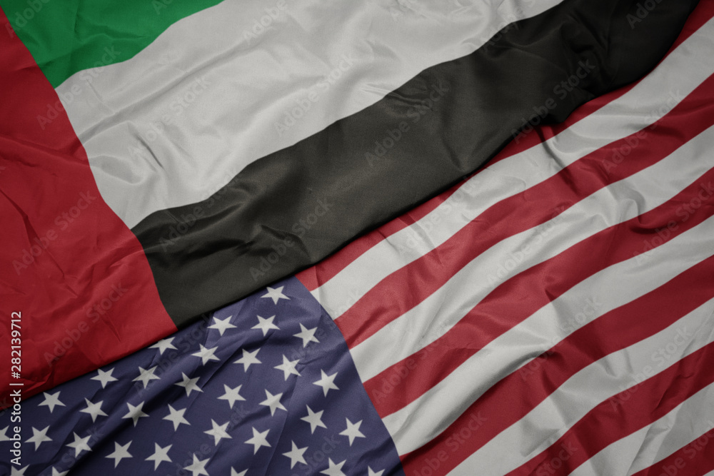 Obraz premium waving colorful flag of united states of america and national flag of united arab emirates.