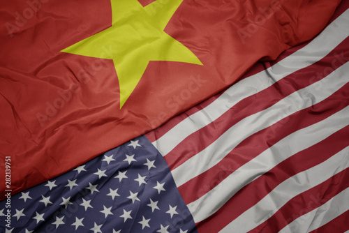 waving colorful flag of united states of america and national flag of vietnam.