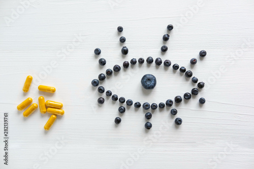 Conceptual photo of the treatment of vision. Products that improve vision. Blueberries and vitamins for eye health. View from above.