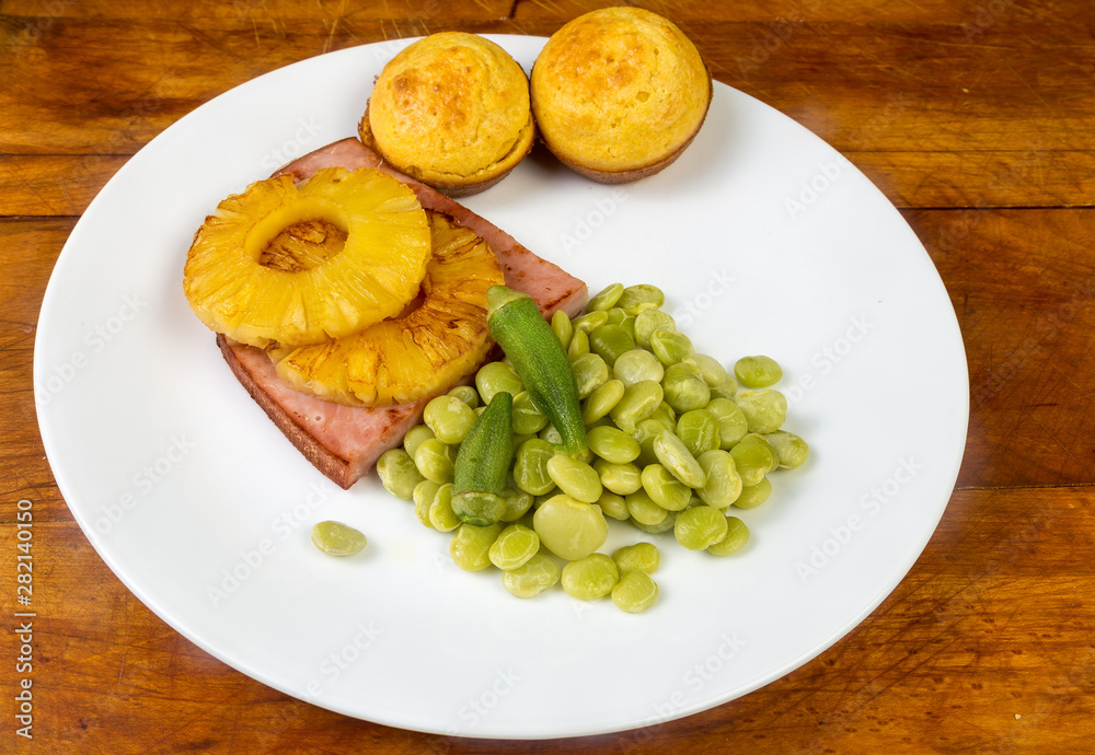 Slice of Baked Ham topped with Grilled Pineapple and Served with Okra Flavored Lima Beans and Cornbread