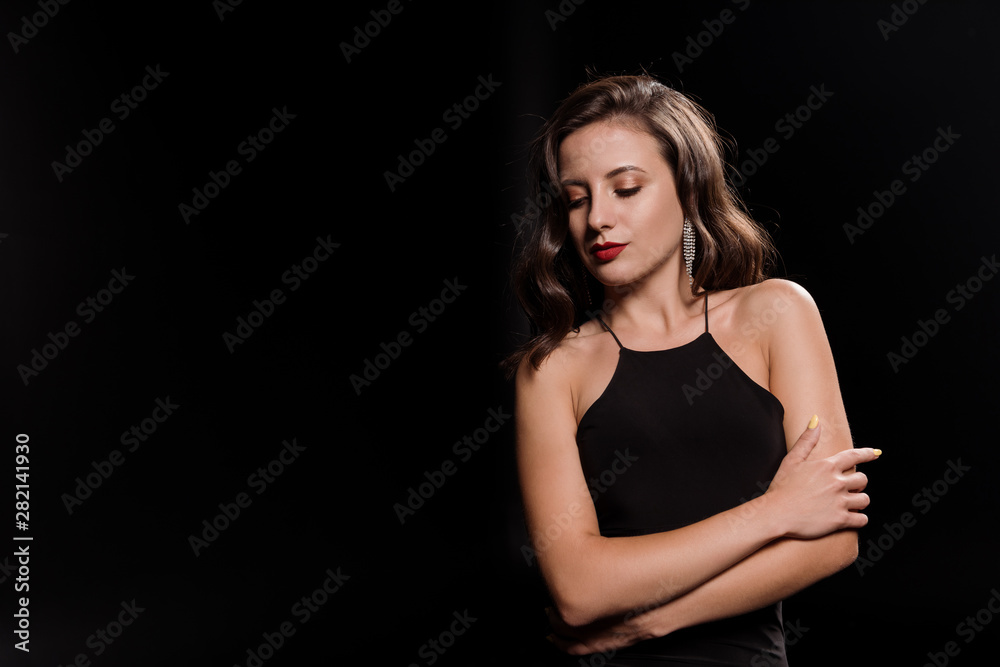 attractive young woman in dress standing with crossed arms isolated on black attractive young woman in dress standing with crossed arms isolated on black