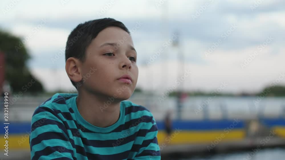 Small boy looking with surprise at Dnipro waters on quay in summer in slo-mo Small boy looking with surprise at Dnipro waters on quay in summer in slo-mo