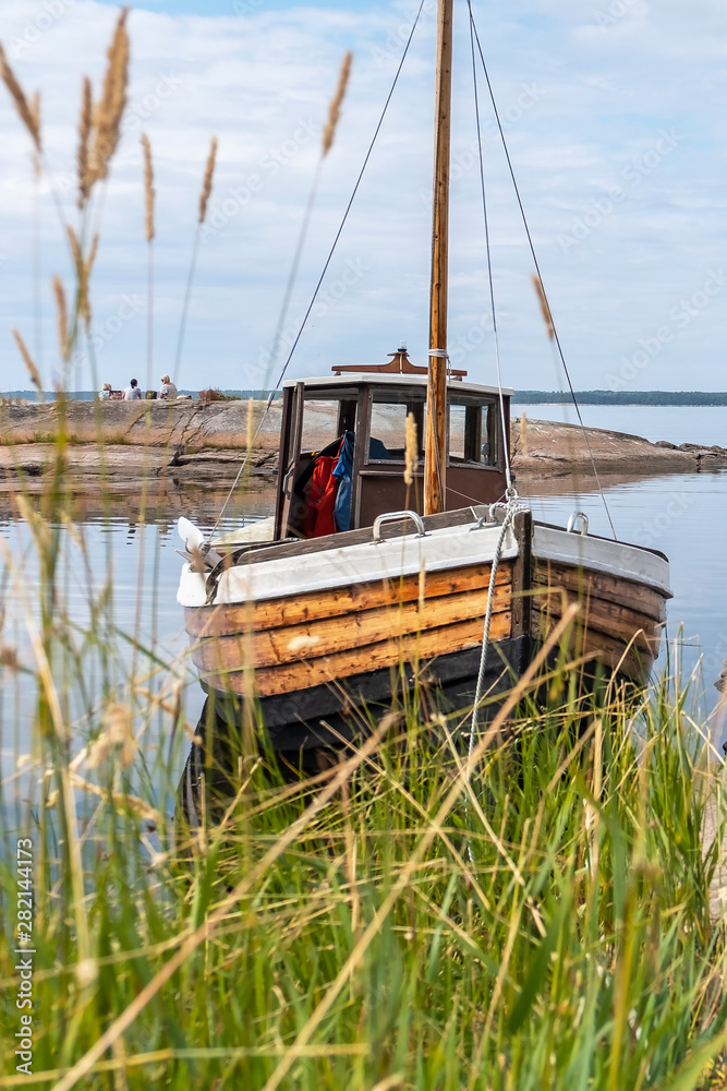 Fototapeta premium Antique, wooden boat. Northern nature, sea bay and huge stones. The coastline of a rocky island. Scandinavian nature