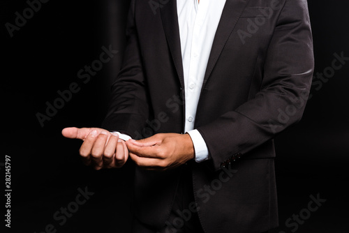 cropped view of mixed race man touching white shirt isolated on black