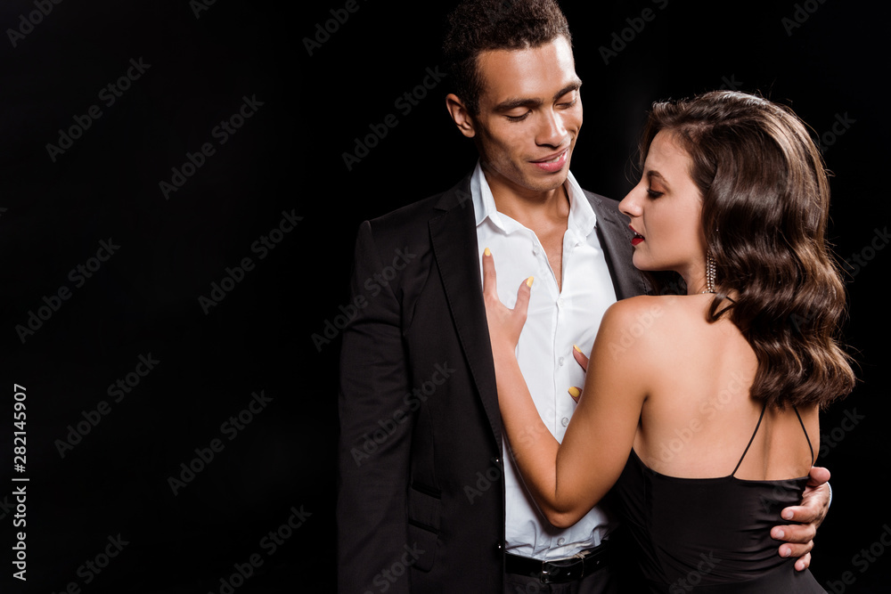 beautiful girl hugging with happy bi-racial man isolated on black