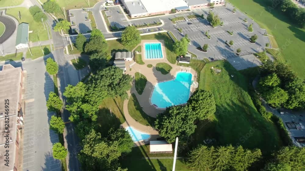 High aerial orbiting drone shot above community swimming pool with ...
