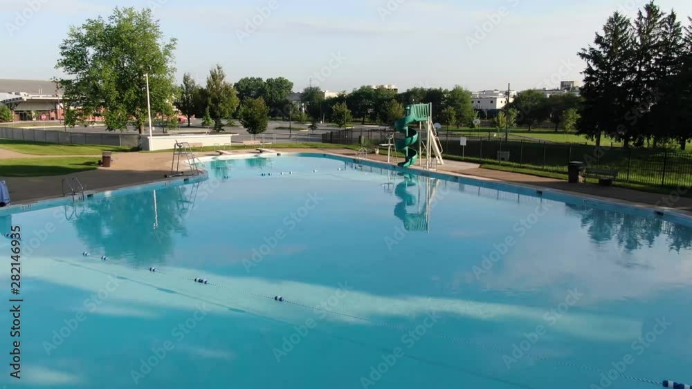 Dolly forward of community pool in bright morning sunlight with diving boards, sliding boards, no people, 4K Dolly forward of community pool in bright morning sunlight with diving boards, sliding boards, no people, 4K