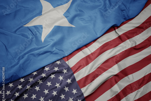 waving colorful flag of united states of america and national flag of somalia. photo