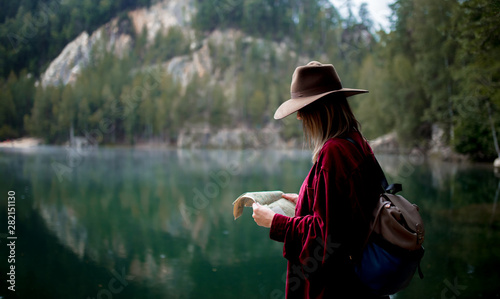 Young woman in hat and red shirt with map near lake