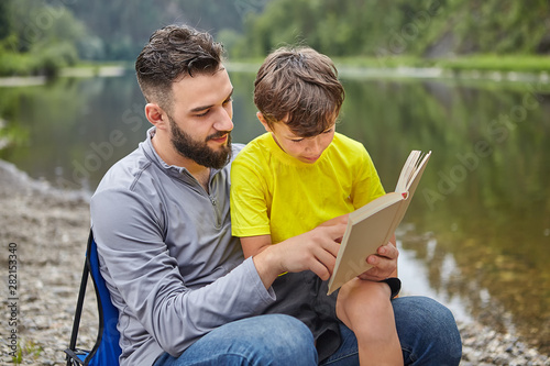 Family are reading book near river. photo