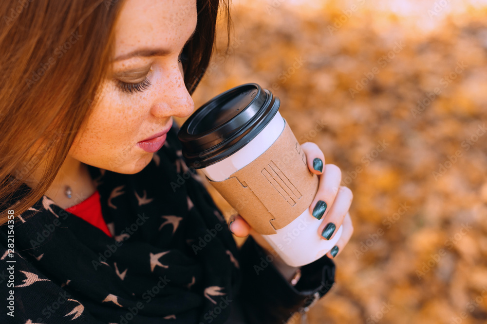 Obraz premium young woman drinking coffee in the park. close up. woman with fr