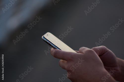 Hands of person typing on a mobile phone, on an urban background, woman, urban technology.