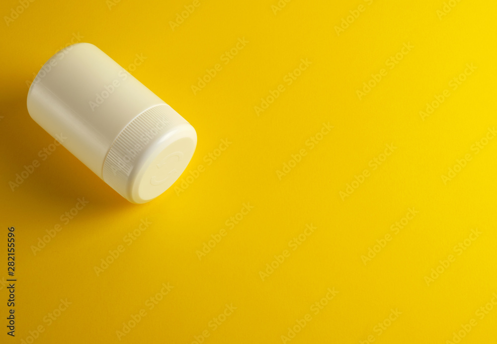 closed white plastic jar for medicines on a yellow background closed white plastic jar for medicines on a yellow background
