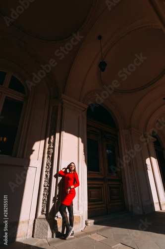 girl in a red dress near a large wooden door in the corridor wit