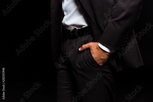 cropped view of mixed race man standing with hand in pocket isolated on black