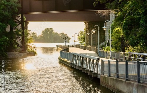 A walkway going along water canal and under the highway overpass photo