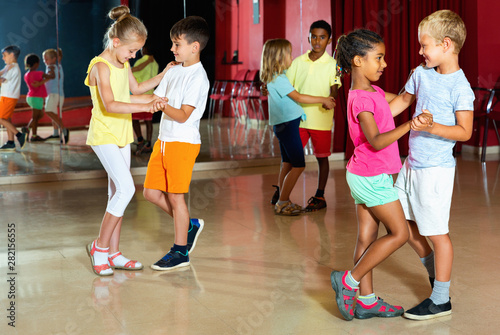 Group of positive childrens trying dancing with partner in classroom