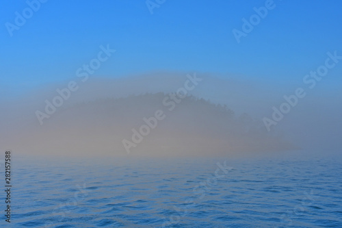Morning fog hugs the coast of Deception Pass as it enters the Salish Sea in Washington State