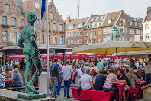 Crowd of people enjoy outdoor activities and hang out at food festival around market plaza near old town hall in Düsseldorf, Germany.