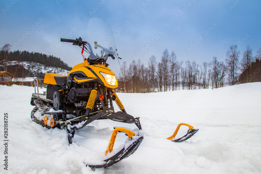 Yellow snowmobile closeup. ATV in the background of a winter landscape. Sale of snowmobiles. Winter entertainment. Winter modes of transport. Snowy winter.