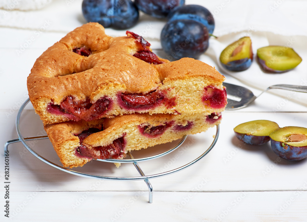 slices of biscuit plum cake on a white wooden board and fresh fruits slices of biscuit plum cake on a white wooden board and fresh fruits