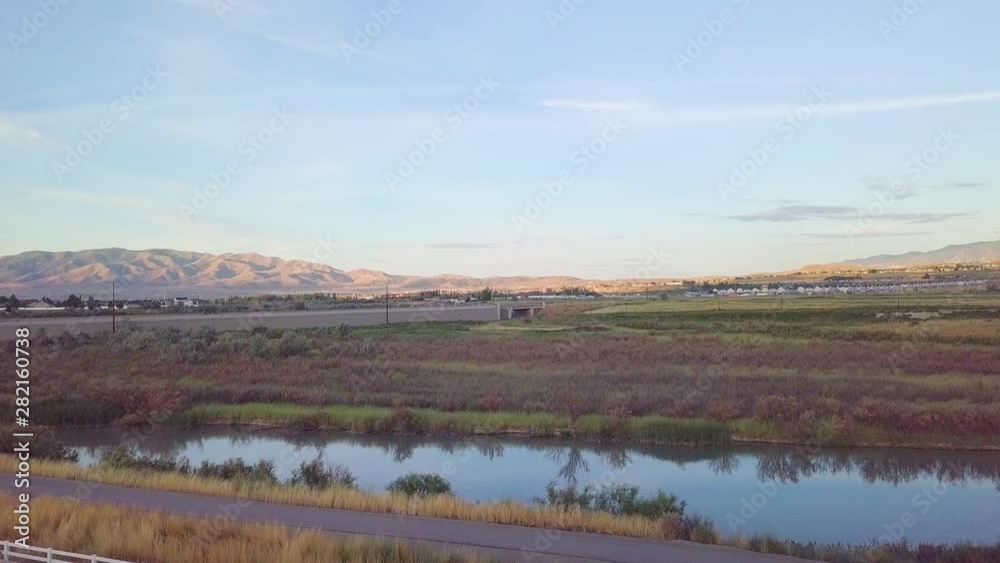 Beautiful meadow with a river, birds flying and mountains in the background - aerial pull back Beautiful meadow with a river, birds flying and mountains in the background - aerial pull back