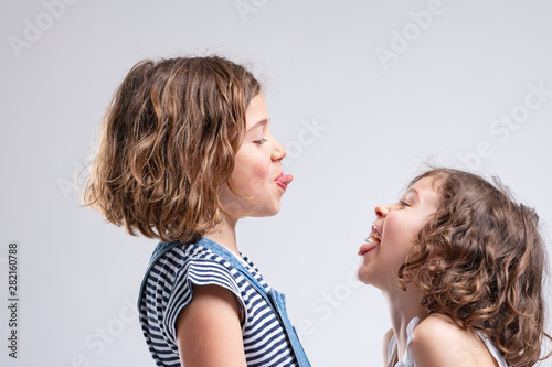 Two naughty young girls sticking out their tongues
