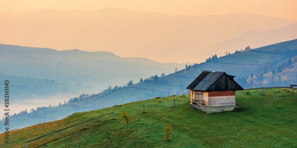 amazing beautiful rural area at dawn. morning in the carpathian mountains. fog in the distant valley. woodshed on the hill