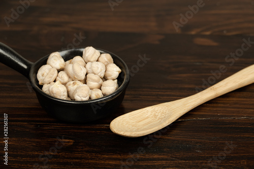 Raw chickpeas in a little ceramic bowl on a dark wooden background. top view, out of range.