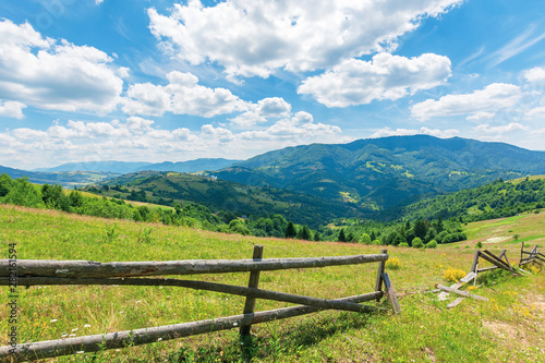 wonderful landscape of rural area at noon. amazing cloudscape above the distant mountain ridge. beautiful sunny weather. wooden fence on the grassy meadow