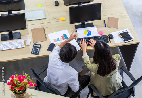 Top rear view of accountant man and woman working on computer analyzing income statement of company in office