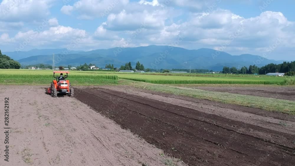 トラクターで農地を耕す日本人の男性　農業