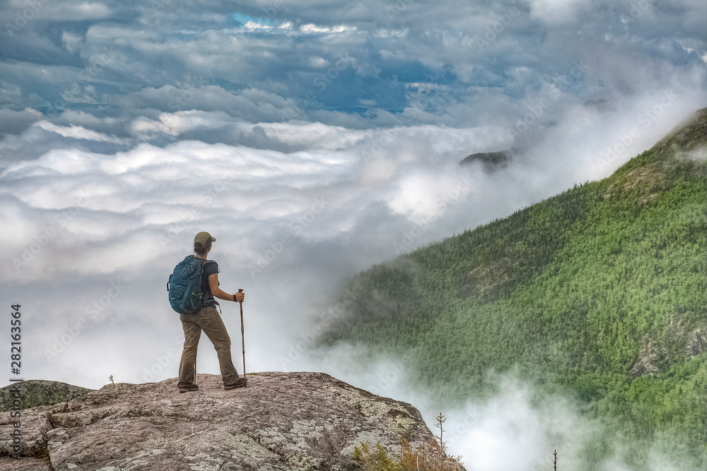 Lone active woman at the edge of the cliff, above the clouds, Quebec, Canada