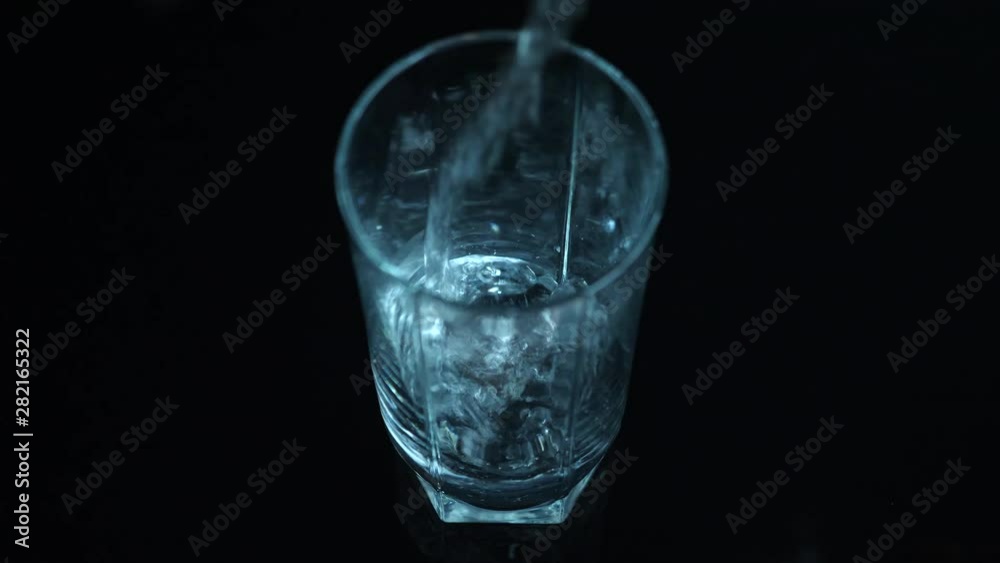 Clean water pouring in empty glass, black backdrop, locked off Clean water pouring in empty glass, black backdrop, locked off