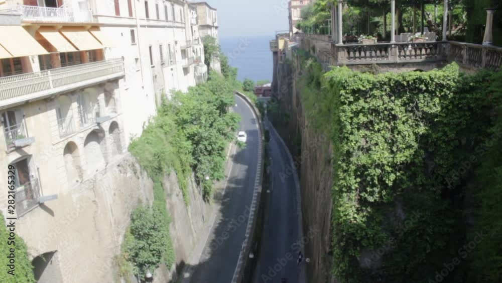Pan Up of Road in Mountain Pass Surrounded by Vines and Vegetation to Rooftop Cafe's and Buildings Pan Up of Road in Mountain Pass Surrounded by Vines and Vegetation to Rooftop Cafe's and Buildings