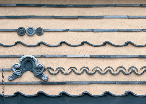 A roofed wall using various types of  tiles surround part of a temple in Tokyo’s nostalgic Yanaka district, Japan.  photo