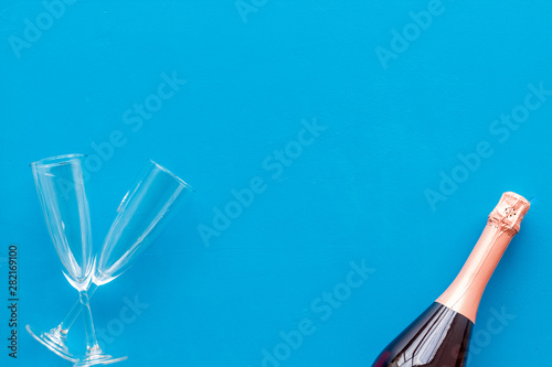 Champagne bottle with glasses for celebration on blue background top view mock up