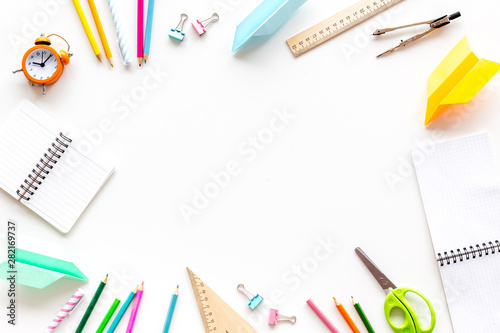 Back to school with stationary, notebook and alarm clock on white student desk background top view mock-up