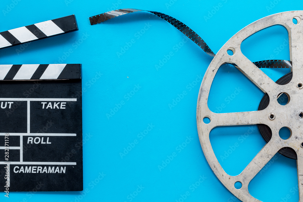 Movie premiere concept with clapperboard, film type on blue background top view