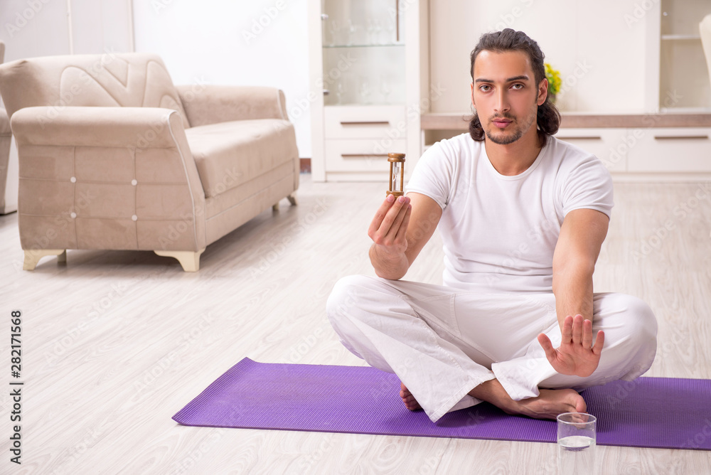 Fototapeta premium Young man doing physical exercises at home