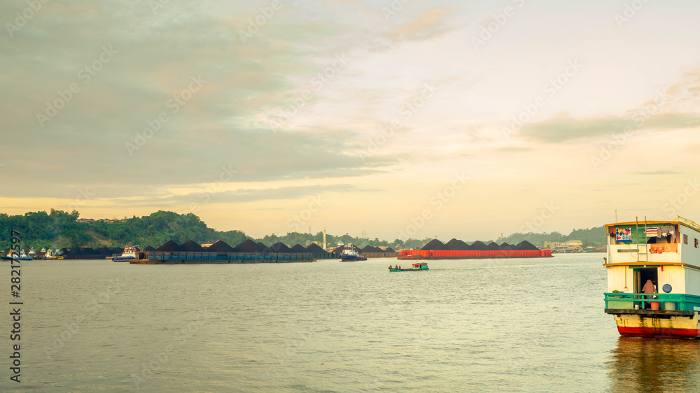 Fototapeta premium the traffic of tugboat dragging barge full of coal at Mahakam River, Samarinda, Indonesia. Industrial and mining background