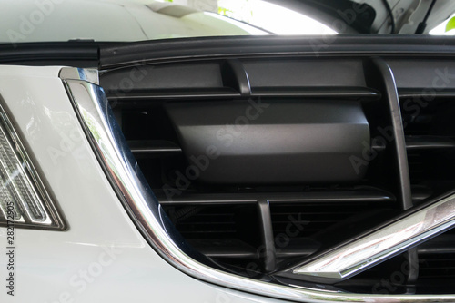 Luxury car adaptive cruise control radar installed on front grille.