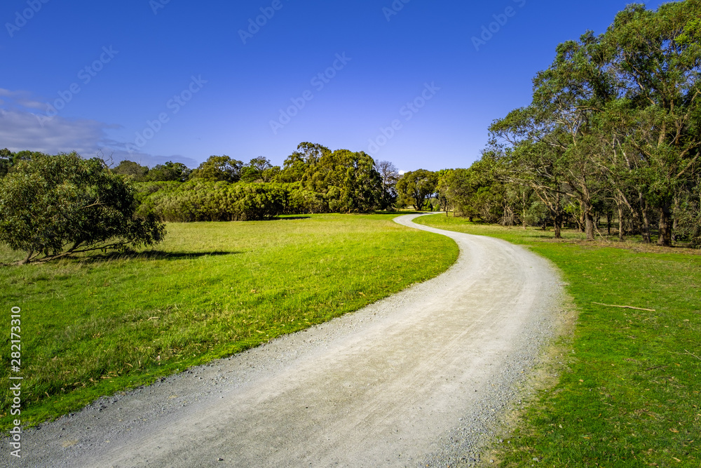 Gravel road winding among grass and trees in Cranbourne, Victoria, Australia