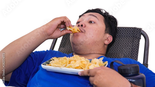 Portrait of lazy Overweight man eating chips and holding water container while laying on a  lazy chair