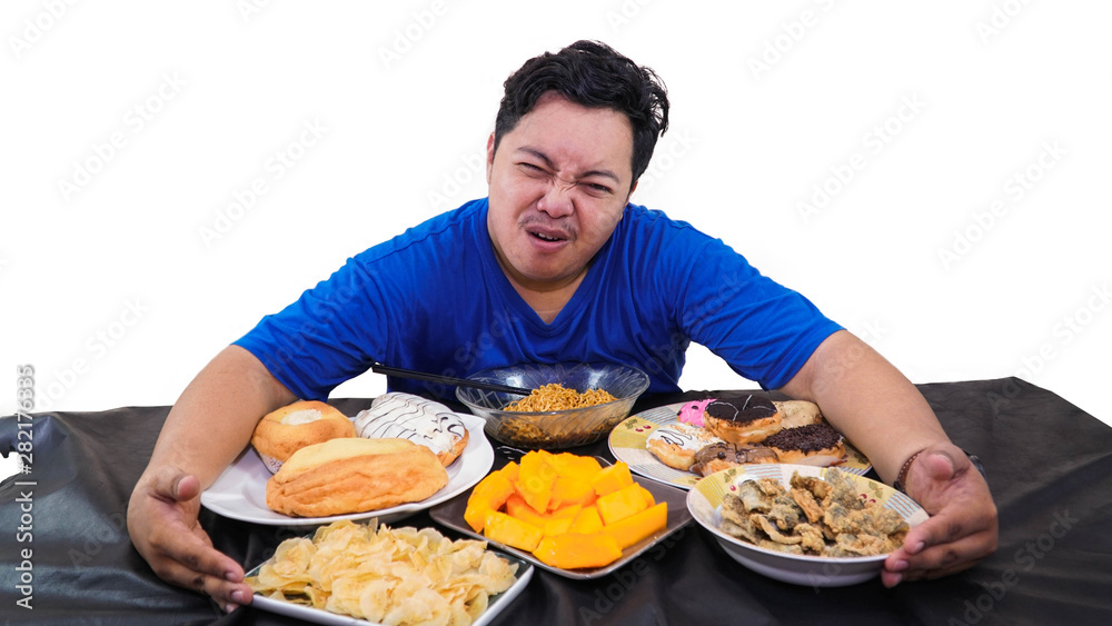 fat or overweight Asian man huging at  a lot of unhealthy food on the table isolated in white, fat man greed