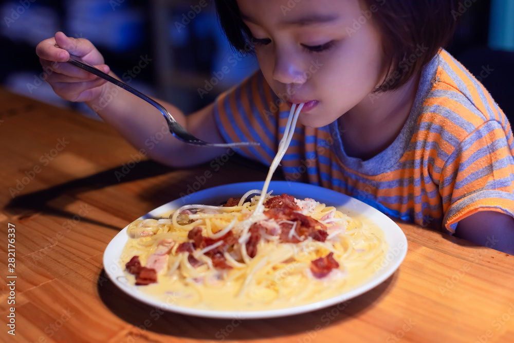 Asian little girl is eating spaghetti bolognese in the restaurant happily. Asian little girl is eating spaghetti bolognese in the restaurant happily.