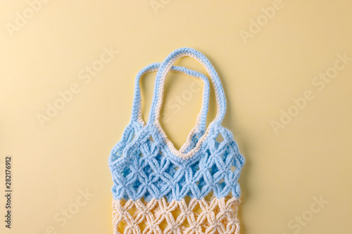 top view of empty yellow blue string bag on yellow background, zero waste eco-friendly trendy shopping minimal concept